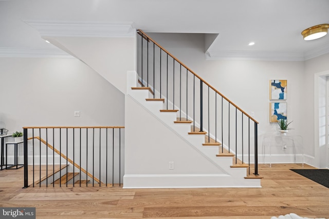 staircase with hardwood / wood-style floors and ornamental molding