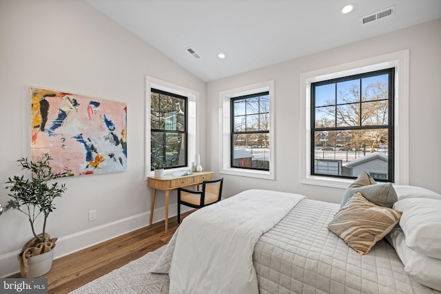 bedroom featuring hardwood / wood-style floors, lofted ceiling, and multiple windows