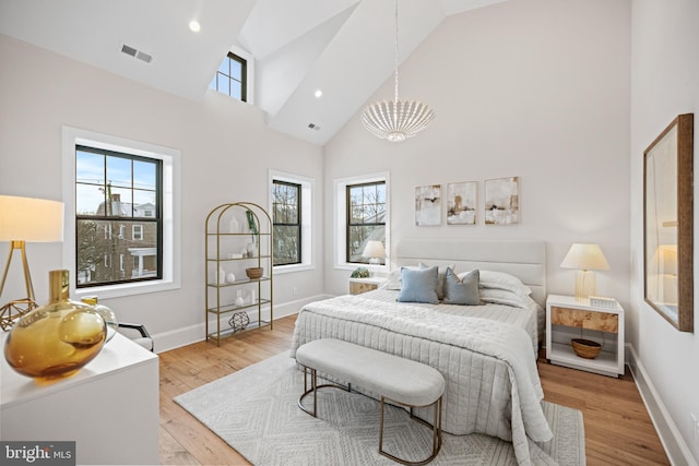 bedroom featuring high vaulted ceiling, light hardwood / wood-style floors, and a notable chandelier