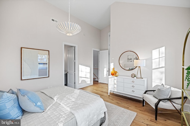 bedroom with hardwood / wood-style flooring, high vaulted ceiling, and a notable chandelier