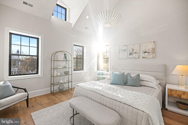 bedroom featuring hardwood / wood-style floors, high vaulted ceiling, and multiple windows