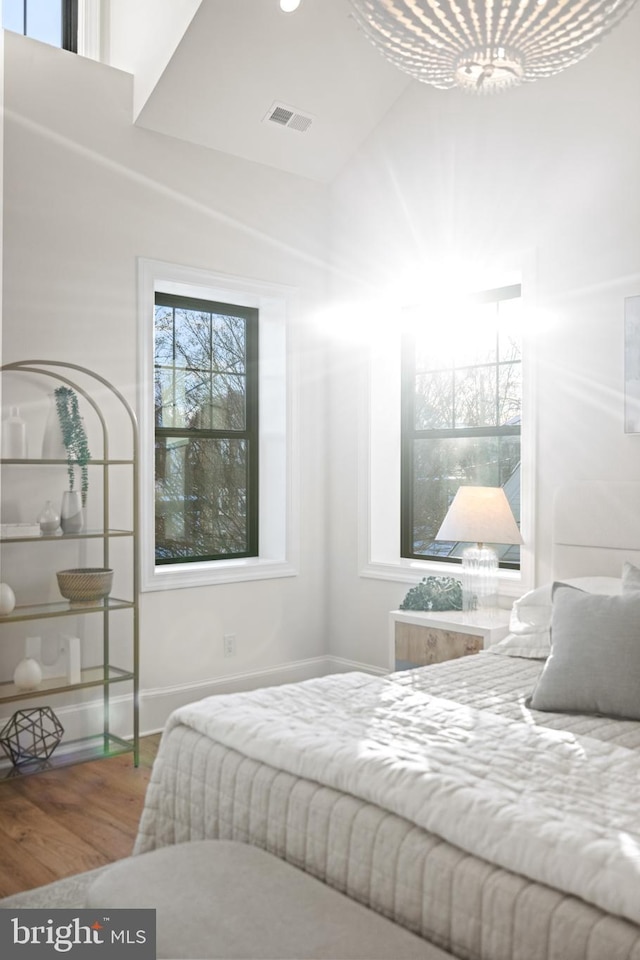 bedroom with hardwood / wood-style flooring and an inviting chandelier