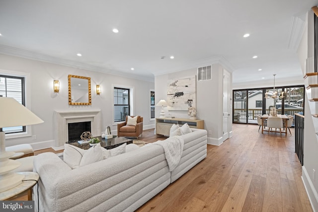 living room with a notable chandelier, light hardwood / wood-style flooring, plenty of natural light, and ornamental molding