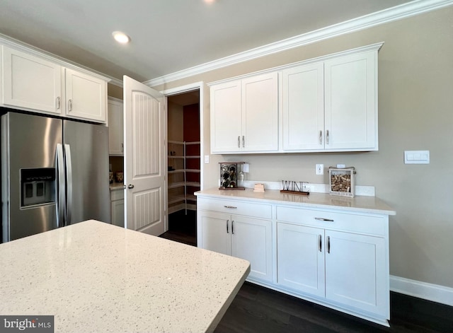 kitchen with light stone counters, ornamental molding, white cabinets, stainless steel fridge with ice dispenser, and dark hardwood / wood-style floors