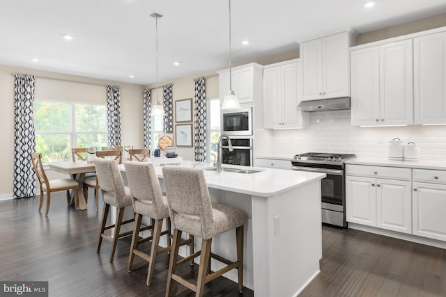 kitchen with a center island with sink, pendant lighting, white cabinetry, and stainless steel appliances