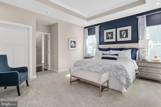 carpeted bedroom featuring a raised ceiling, crown molding, and connected bathroom