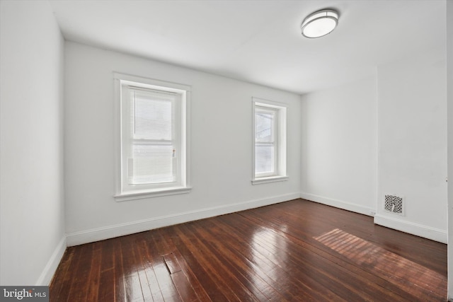 empty room with dark hardwood / wood-style flooring and a healthy amount of sunlight