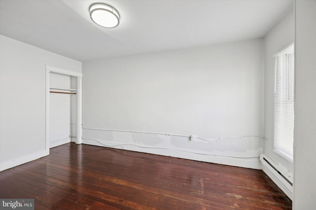 unfurnished bedroom with a closet, a baseboard radiator, multiple windows, and dark hardwood / wood-style floors