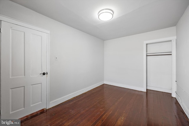 unfurnished bedroom featuring dark hardwood / wood-style flooring and a closet