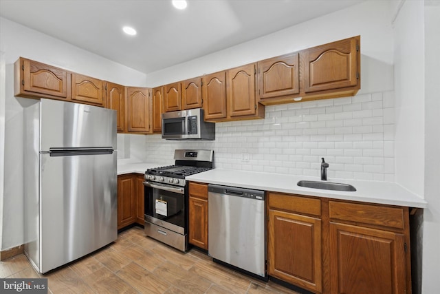 kitchen featuring sink, light wood-type flooring, stainless steel appliances, and tasteful backsplash