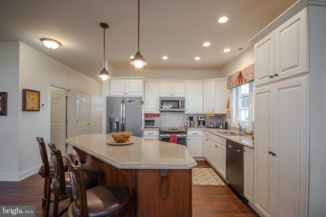 kitchen featuring white cabinets, a center island, light stone counters, and stainless steel appliances