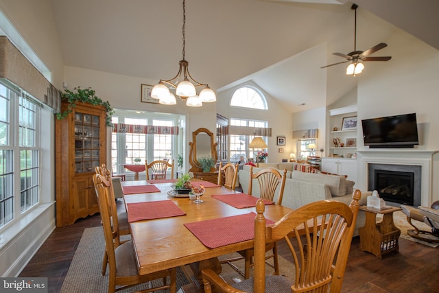 dining area with vaulted ceiling, built in features, dark wood-type flooring, and ceiling fan with notable chandelier