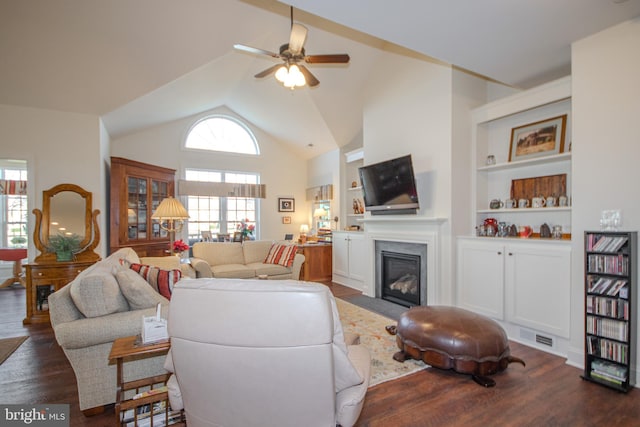 living room featuring ceiling fan, built in features, dark wood-type flooring, and vaulted ceiling