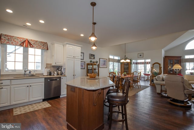 kitchen featuring white cabinetry, sink, stainless steel dishwasher, pendant lighting, and a kitchen island