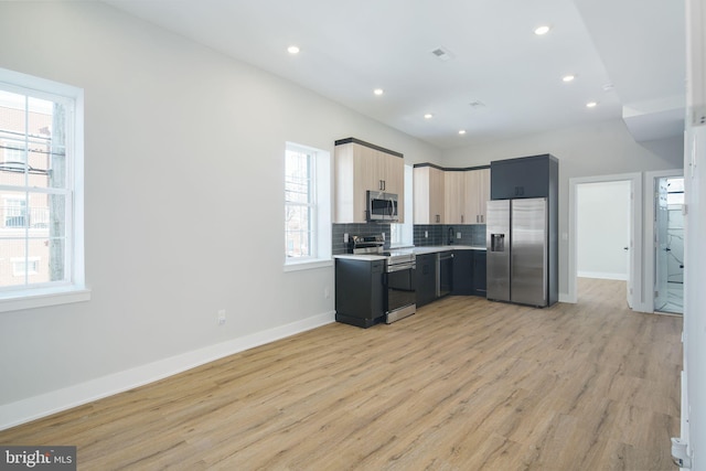 kitchen featuring decorative backsplash, appliances with stainless steel finishes, light brown cabinets, and light hardwood / wood-style flooring