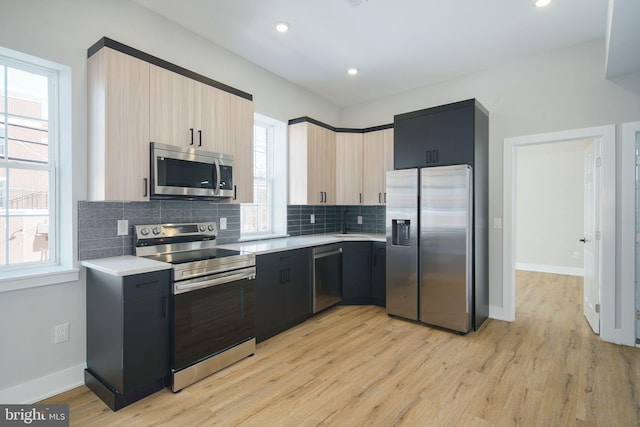 kitchen featuring decorative backsplash, light brown cabinets, stainless steel appliances, and light hardwood / wood-style floors