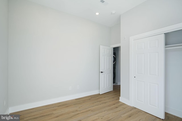 unfurnished bedroom with light wood-type flooring and a closet