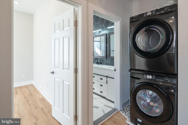 laundry room featuring stacked washer and dryer and light hardwood / wood-style floors