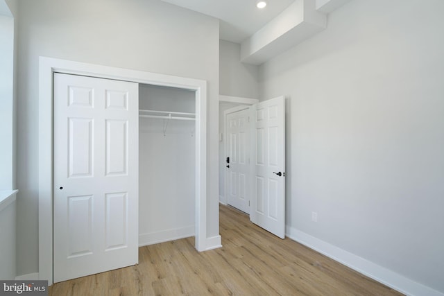 unfurnished bedroom with light wood-type flooring and a closet