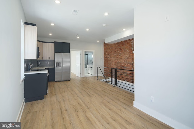 kitchen with backsplash, light hardwood / wood-style flooring, stainless steel appliances, and sink