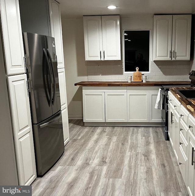 kitchen with wood counters, stainless steel fridge, light hardwood / wood-style floors, and white cabinets