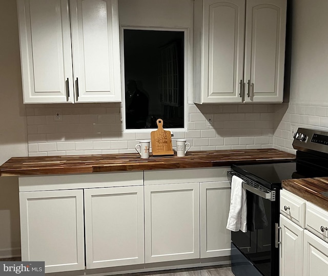 kitchen with range with electric cooktop, wooden counters, decorative backsplash, and white cabinets