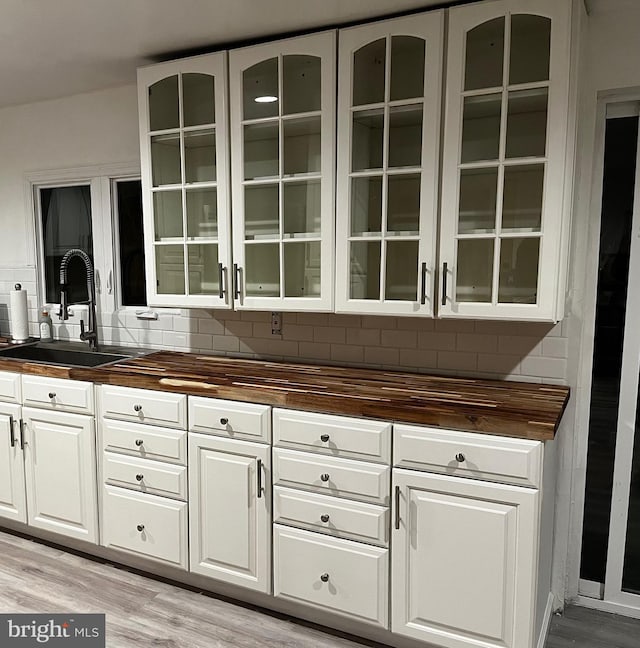 bar featuring tasteful backsplash, sink, light hardwood / wood-style floors, and wooden counters