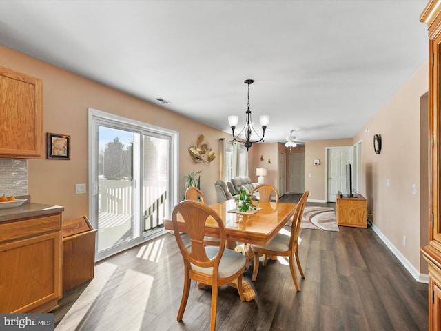 dining space with ceiling fan with notable chandelier and dark wood-type flooring