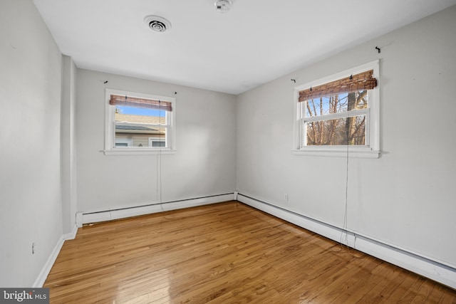 empty room featuring a healthy amount of sunlight, light hardwood / wood-style flooring, and a baseboard radiator