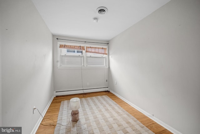 spare room featuring light wood-type flooring and a baseboard heating unit