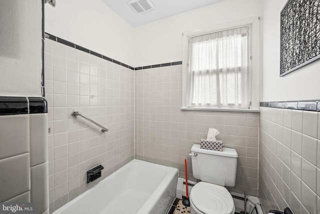 bathroom with toilet, tile walls, and a tub