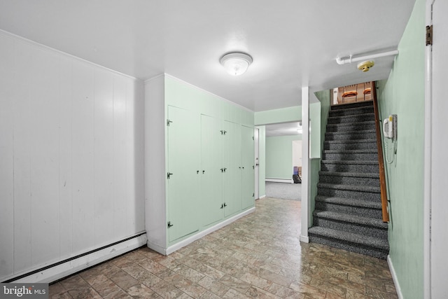 stairway with a baseboard heating unit and wood walls