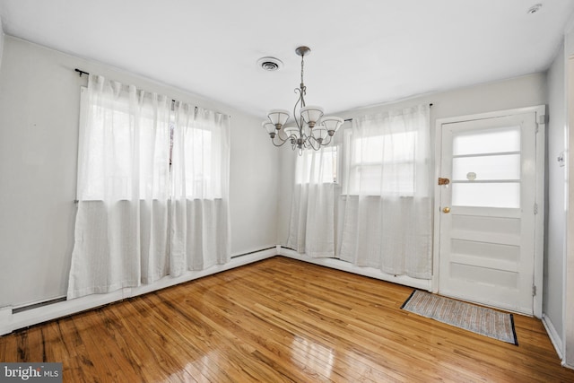 unfurnished dining area featuring a chandelier, a baseboard radiator, and light hardwood / wood-style floors