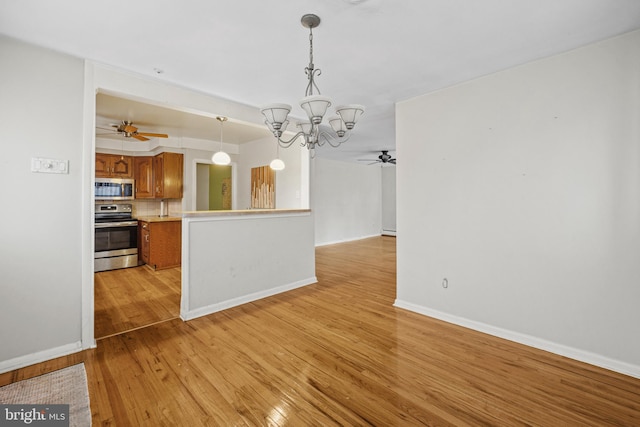 kitchen with tasteful backsplash, light hardwood / wood-style floors, decorative light fixtures, ceiling fan with notable chandelier, and appliances with stainless steel finishes