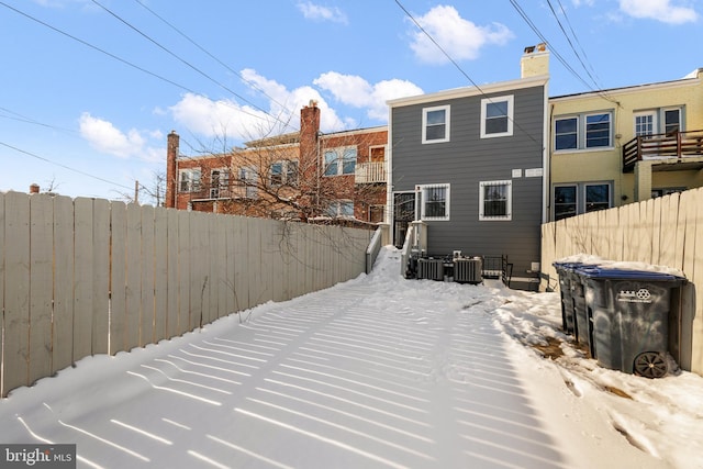 snow covered back of property featuring central AC