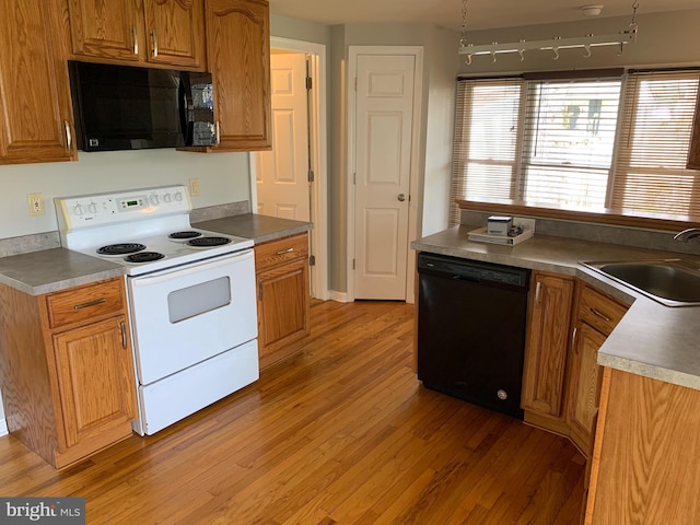 kitchen with sink, black appliances, and light hardwood / wood-style floors