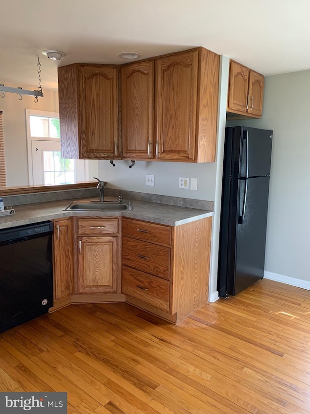 kitchen featuring sink, light hardwood / wood-style flooring, and black appliances