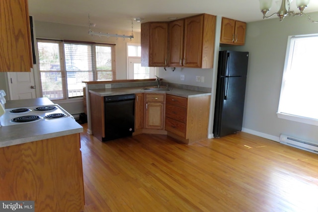 kitchen featuring black appliances, sink, hanging light fixtures, light hardwood / wood-style floors, and a chandelier