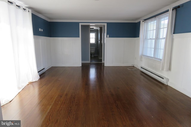 spare room featuring dark hardwood / wood-style flooring, baseboard heating, and a wealth of natural light