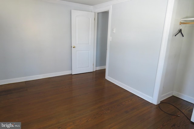 unfurnished room with ornamental molding and dark wood-type flooring