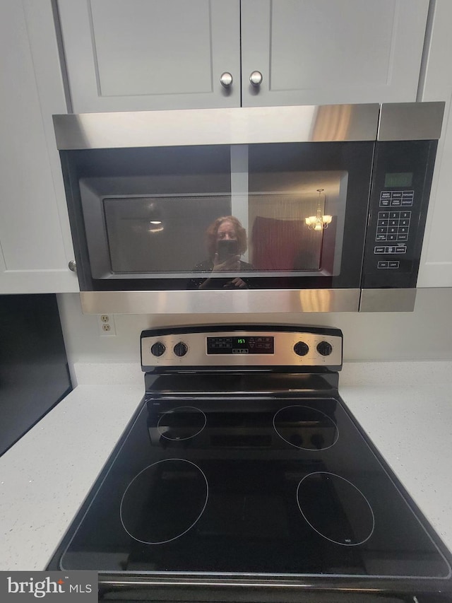 room details with stainless steel appliances, light stone counters, and white cabinetry