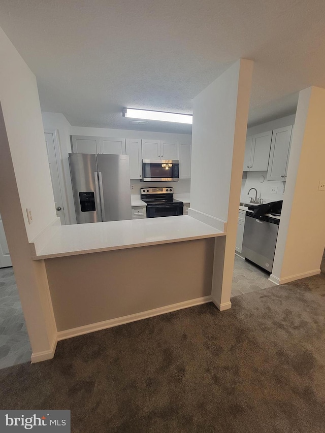 kitchen featuring light carpet, white cabinetry, stainless steel appliances, and light countertops