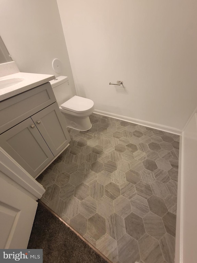 half bathroom featuring baseboards, vanity, and toilet