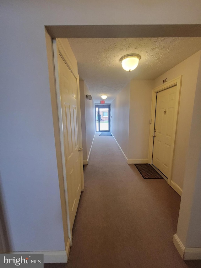 hall with carpet and a textured ceiling