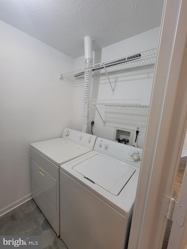 laundry room featuring washer and dryer, laundry area, a textured ceiling, and baseboards