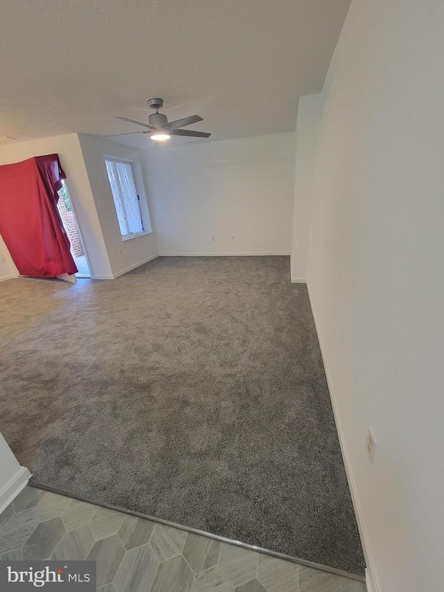 carpeted spare room with ceiling fan and baseboards