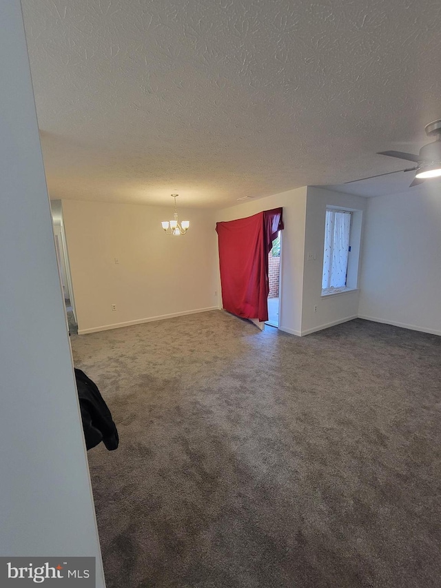 spare room with carpet flooring, a textured ceiling, baseboards, and ceiling fan with notable chandelier