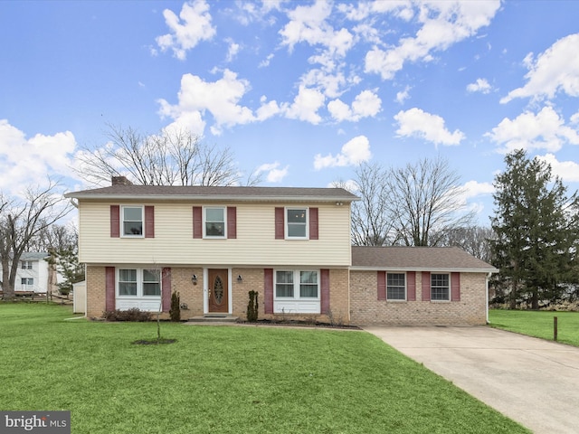 colonial inspired home with a chimney, a front lawn, concrete driveway, and brick siding