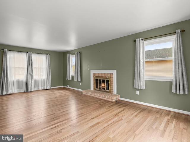 unfurnished living room featuring a fireplace, baseboards, and wood finished floors