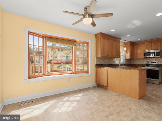 kitchen featuring stainless steel appliances, a peninsula, backsplash, and visible vents